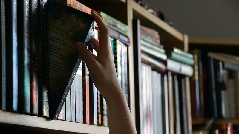 Hand pulling a book off a shelf