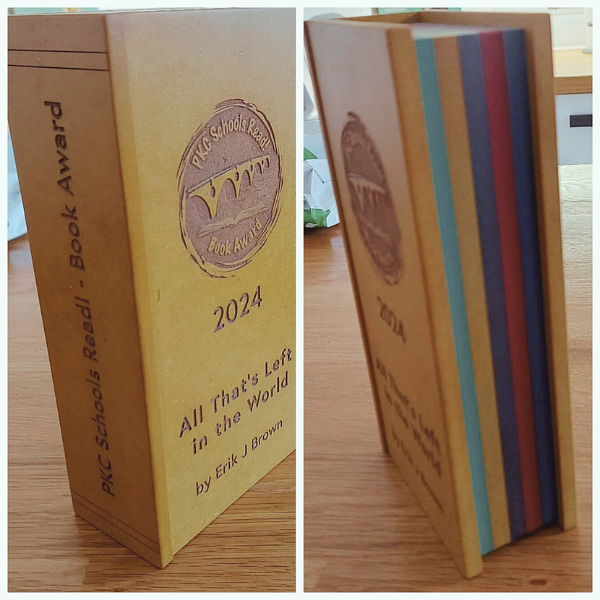 A collage showing the PKC School Reads! trophy shaped like a book with rainbow pages. The 2024 trophy was awarded to the novel 'All That's Left in the World' by Erik J Brown. 